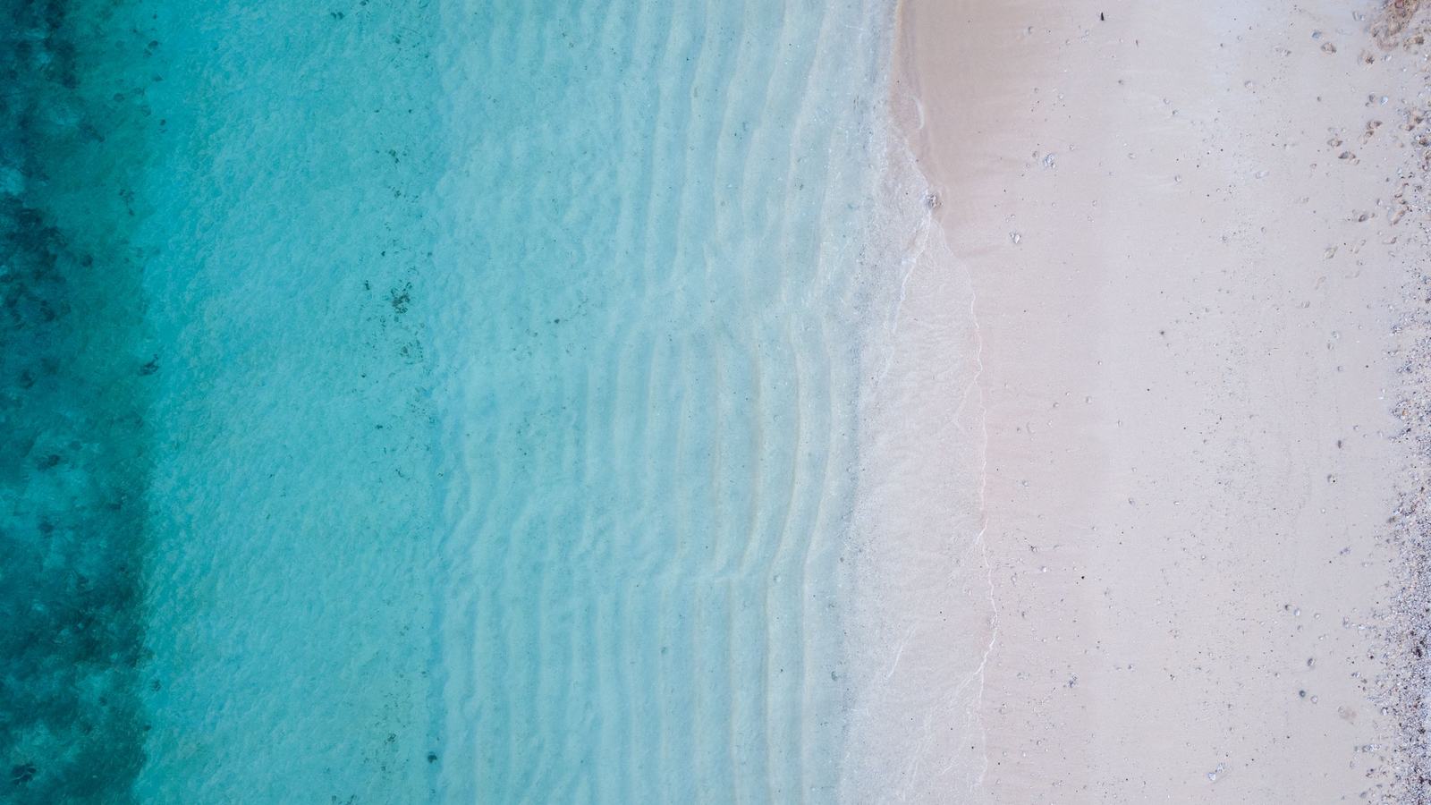 Aerial view of turquoise lagoon water and beach on the Fiji coast